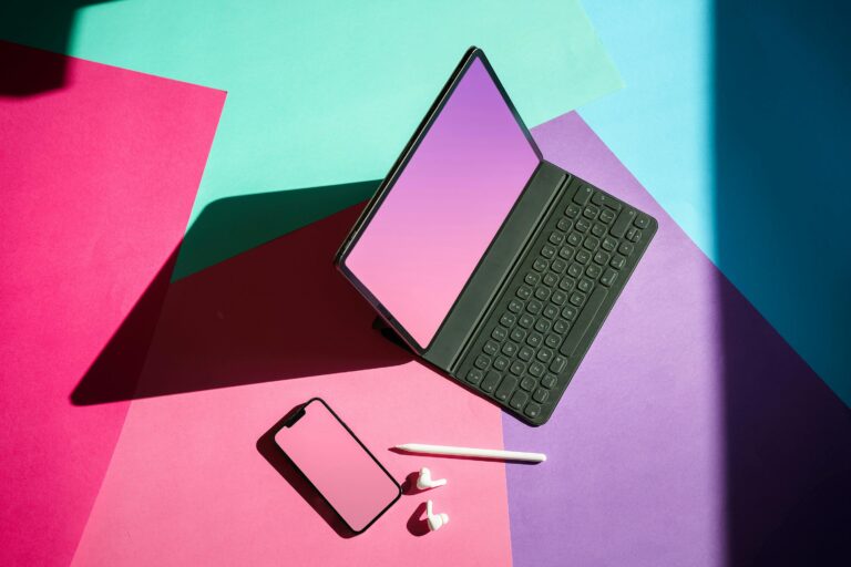 Vibrant flat lay featuring a tablet, smartphone, and stylus on a colorful background.